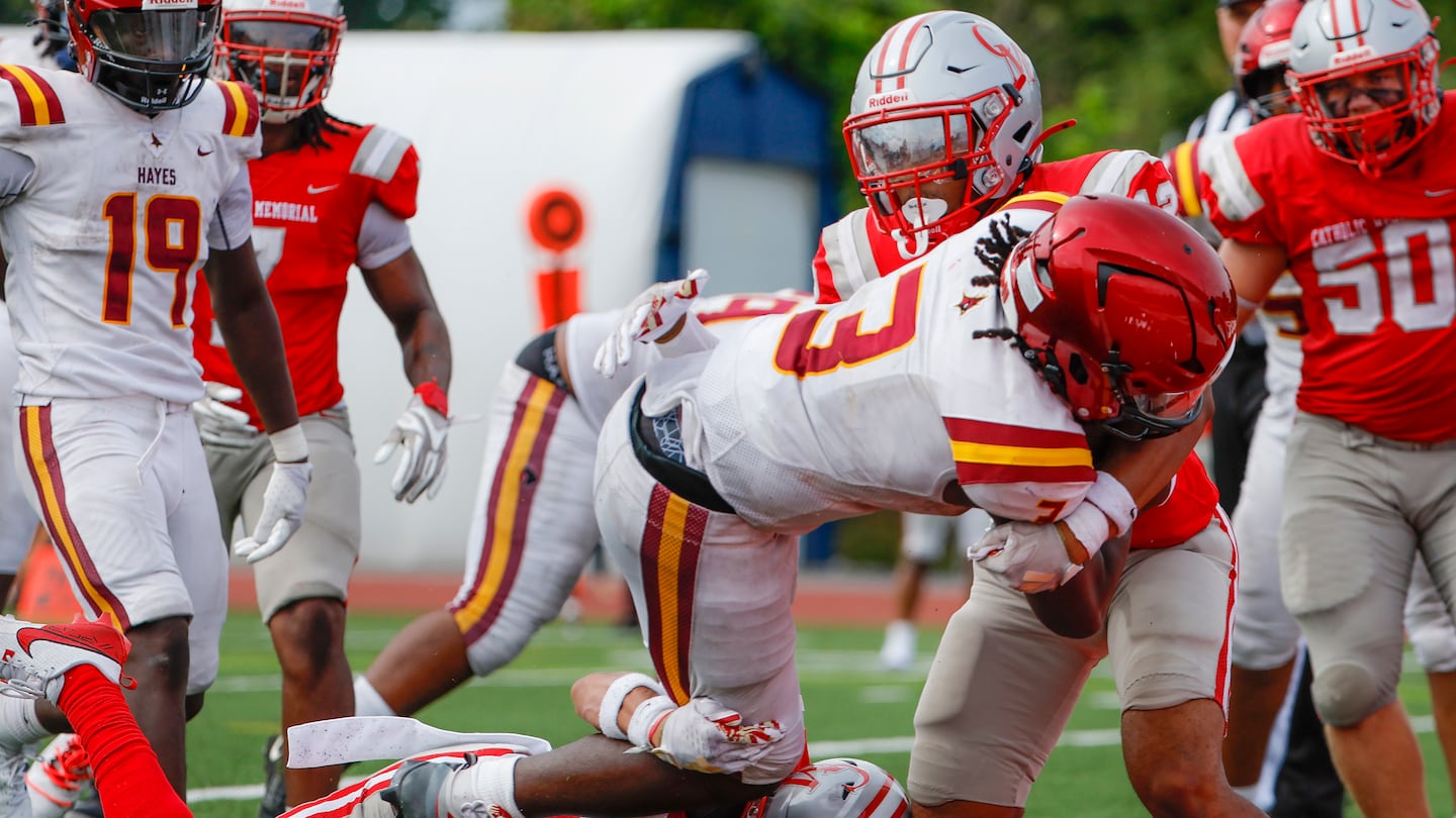 Cardinal Hayes quarterback Rich Berlin lunges for the end zone on his rushing touchdown, breaking through the tackle of Catholic Memorial's Jaiden Johnson (No. 26) and DJ Overall (No. 12) during the second half of CM's season-opening loss Saturday in West Roxbury.