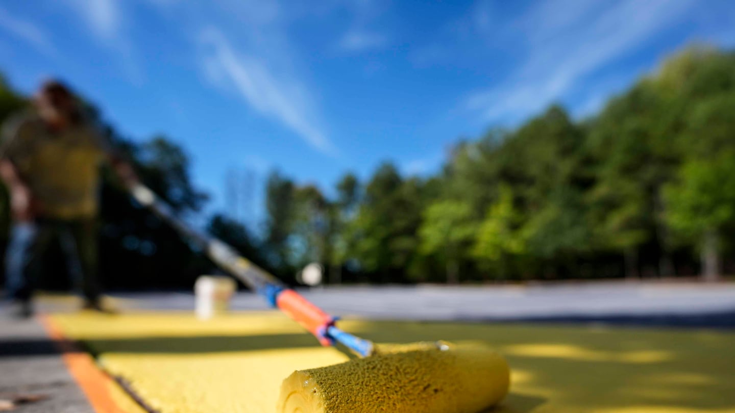 On Wednesday, Ronnie Jefferies painted the parking lot at Science, Arts and Entrepreneurship School in Mableton, Ga, to help cool it by making it more reflective.