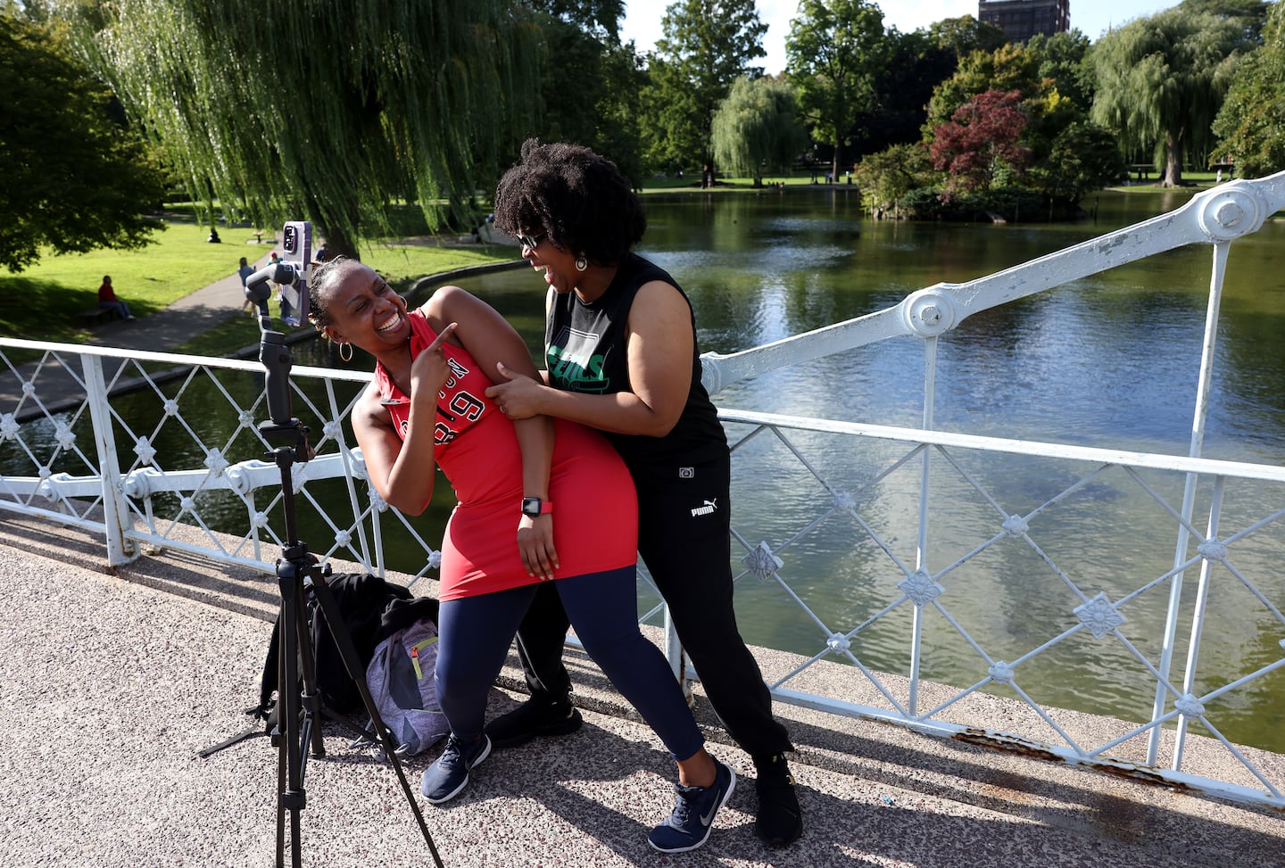 Diana Paris, left, of Randolph and her cousin Stanislass Jones, of Houston, Texas, break down laughing as they record a video together in the Public Garden on a picture-perfect day Tuesday.