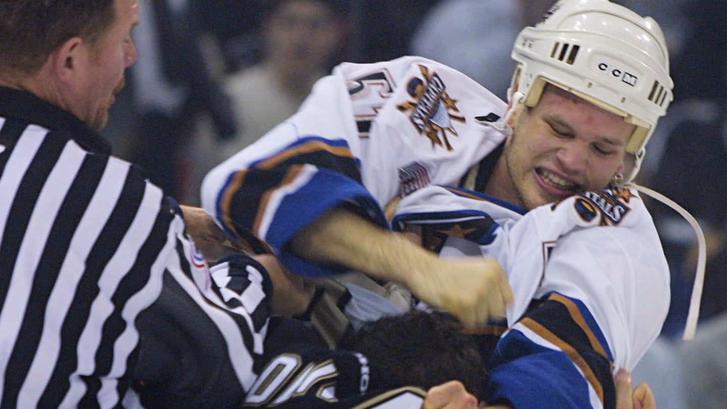 Washington Capitals' Stephen Peat punches Pittsburgh Penguins' Krzysztof Oliwa as linesman Dan McCourt attempts to break it up, Dec. 21, 2001.