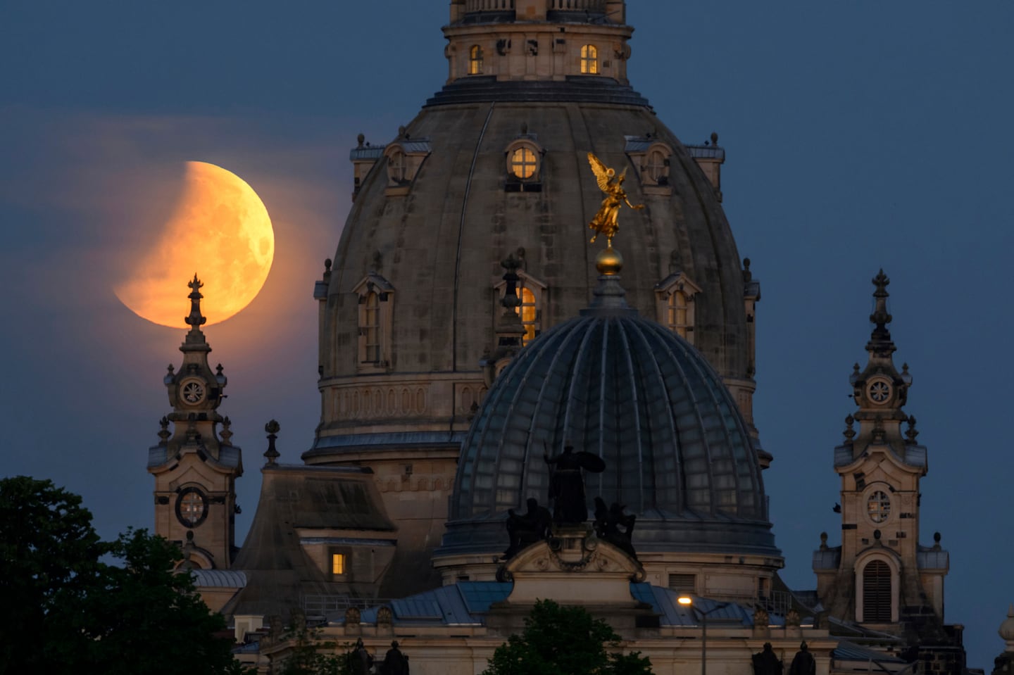 The moon sets in the morning during a partial lunar eclipse behind the Frauenkirche and the dome of the Kunstakedmie in Dresden, Germany.