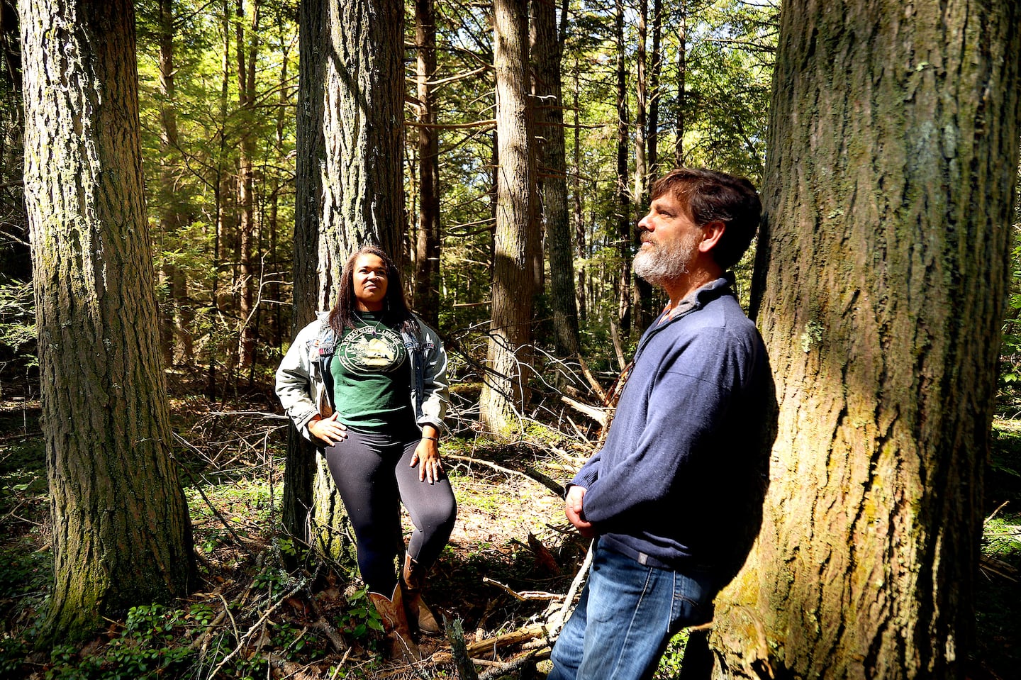 Keshia De Freece Lawrence (left), the Harvard Forest's Indigenous education specialist, paused with Neil Pederson, a forest ecologist, to observe the state of a grove of decades-old hemlock trees in the forest. The pair are in the early stages of a research project focused on the decline of the red-tailed hawk in the eastern woodlands.