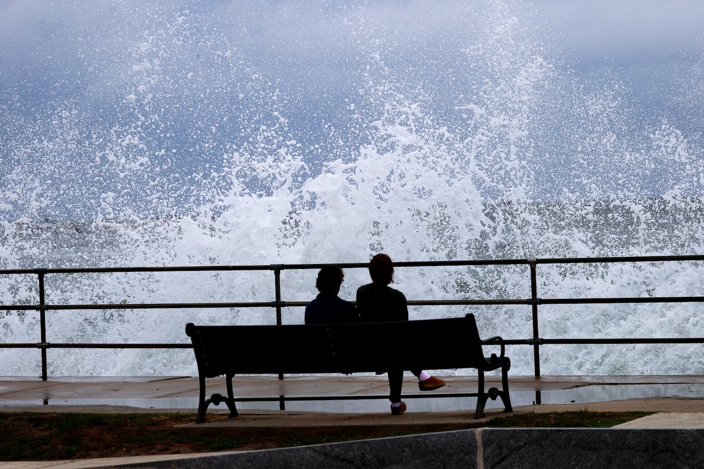 Isaac Eliason and Charlie Dunn, both from Lynn, watch the surf from an unusually strong high tide, called a "king tide," in Swampscott Friday afternoon.