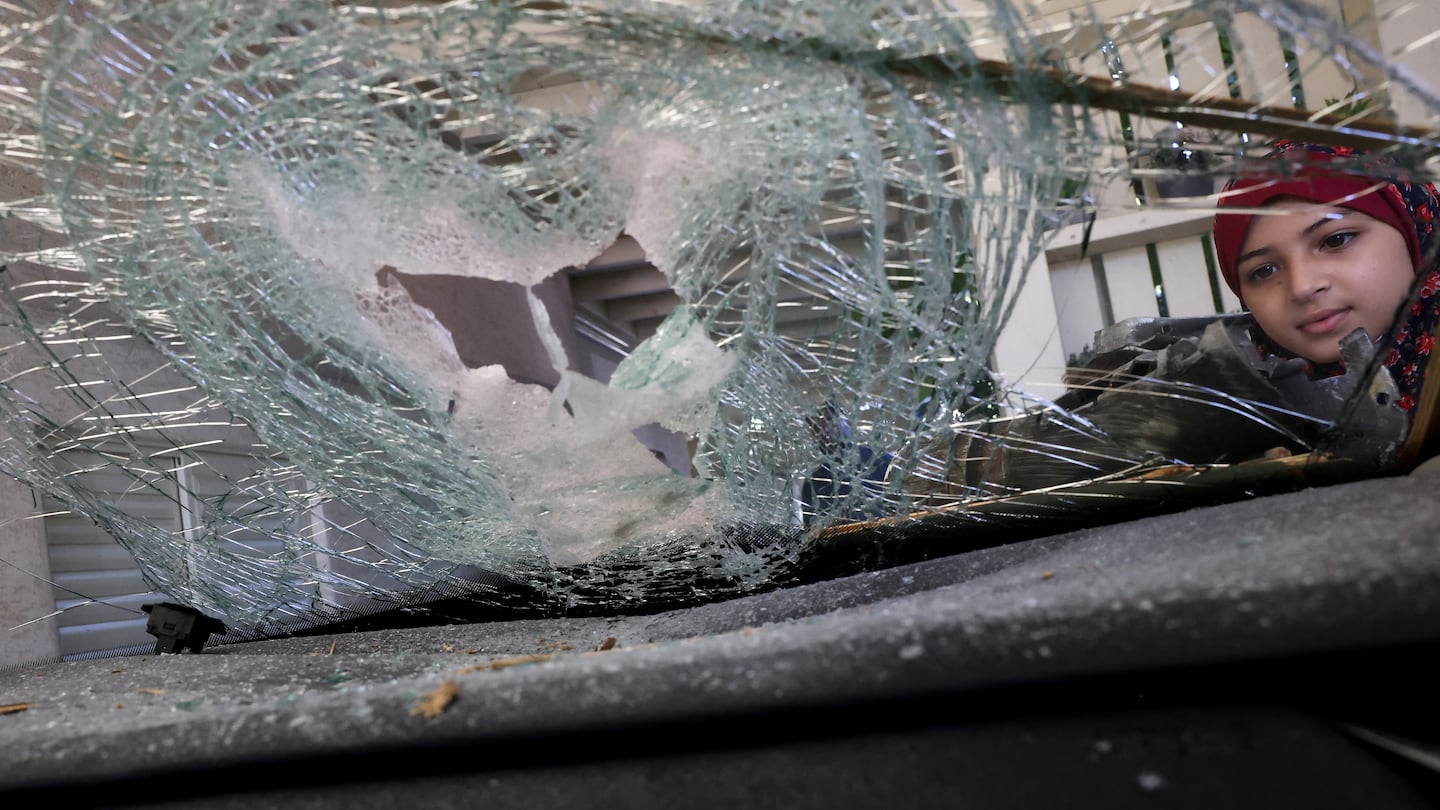 A girl stands at the scene after a rocket fired from southern Lebanon hit a vehicle at a house in the Arab-Israeli village of Kaukab Abu el-Hija in northern Israel on September 25, 2024.