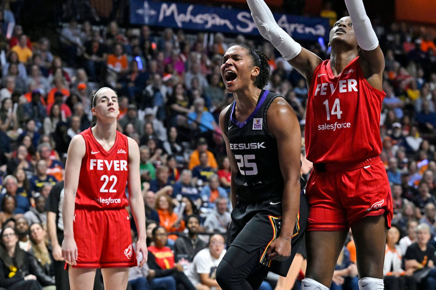 Alyssa Thomas (center) celebrates a basket while being fouled during the second half of Wednesday's Sun victory over Caitlin Clark (left) and the Indiana Fever in Uncasville, Conn.