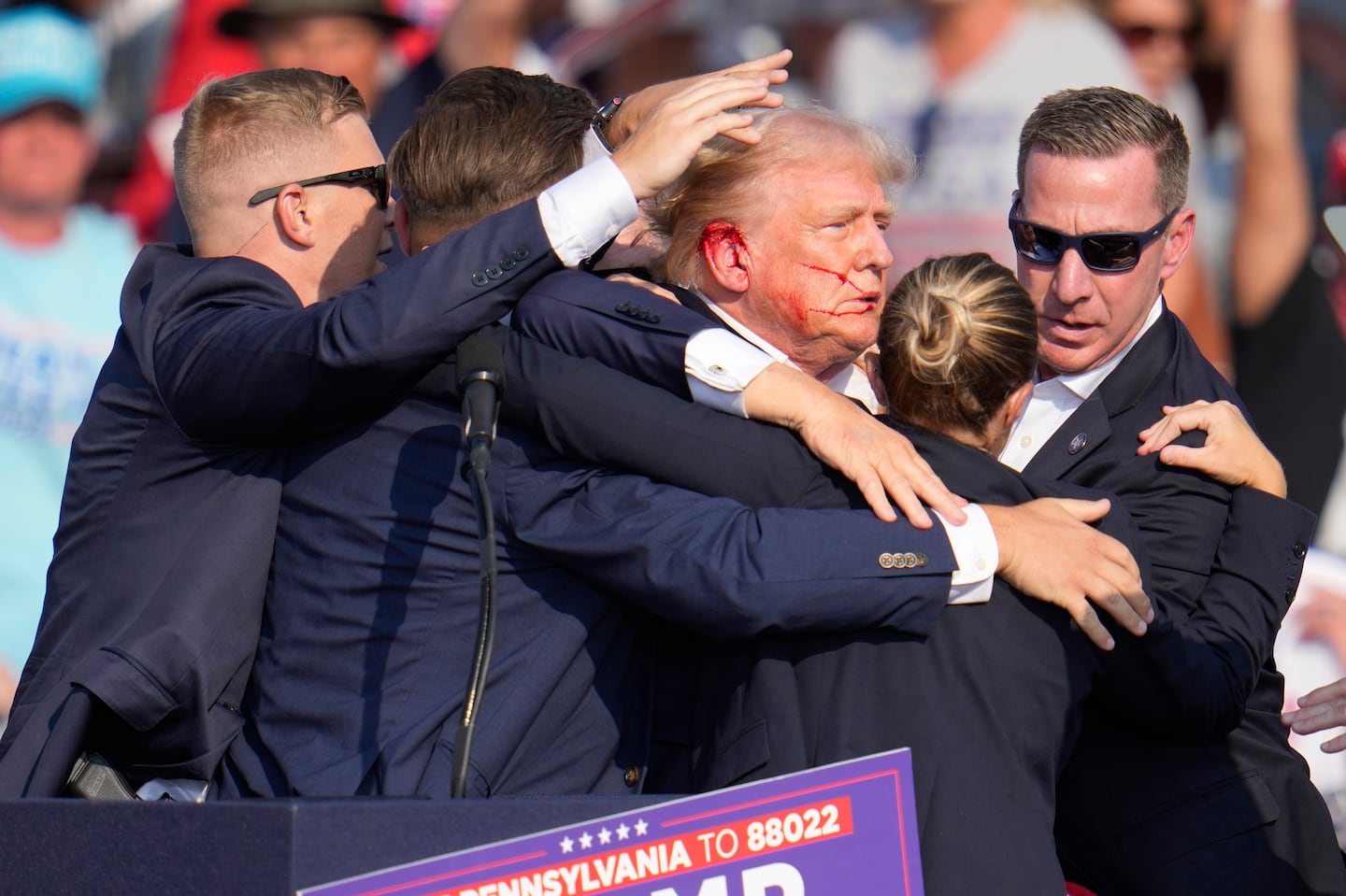 Former president Donald Trump is surrounded by US Secret Service agents as he is helped off the stage at a campaign rally in Butler, Pa., on July 13.