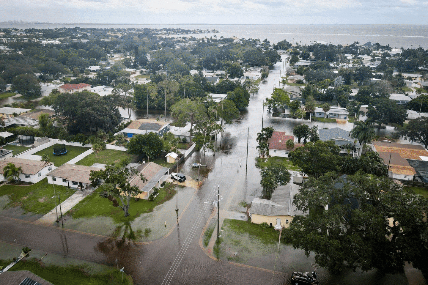 Camryn Frick, left, and Jillian Sternick, hold hands as they cross a flooded street together along Bayshore Boulevard on Sept. 26, in Tampa, Fla.