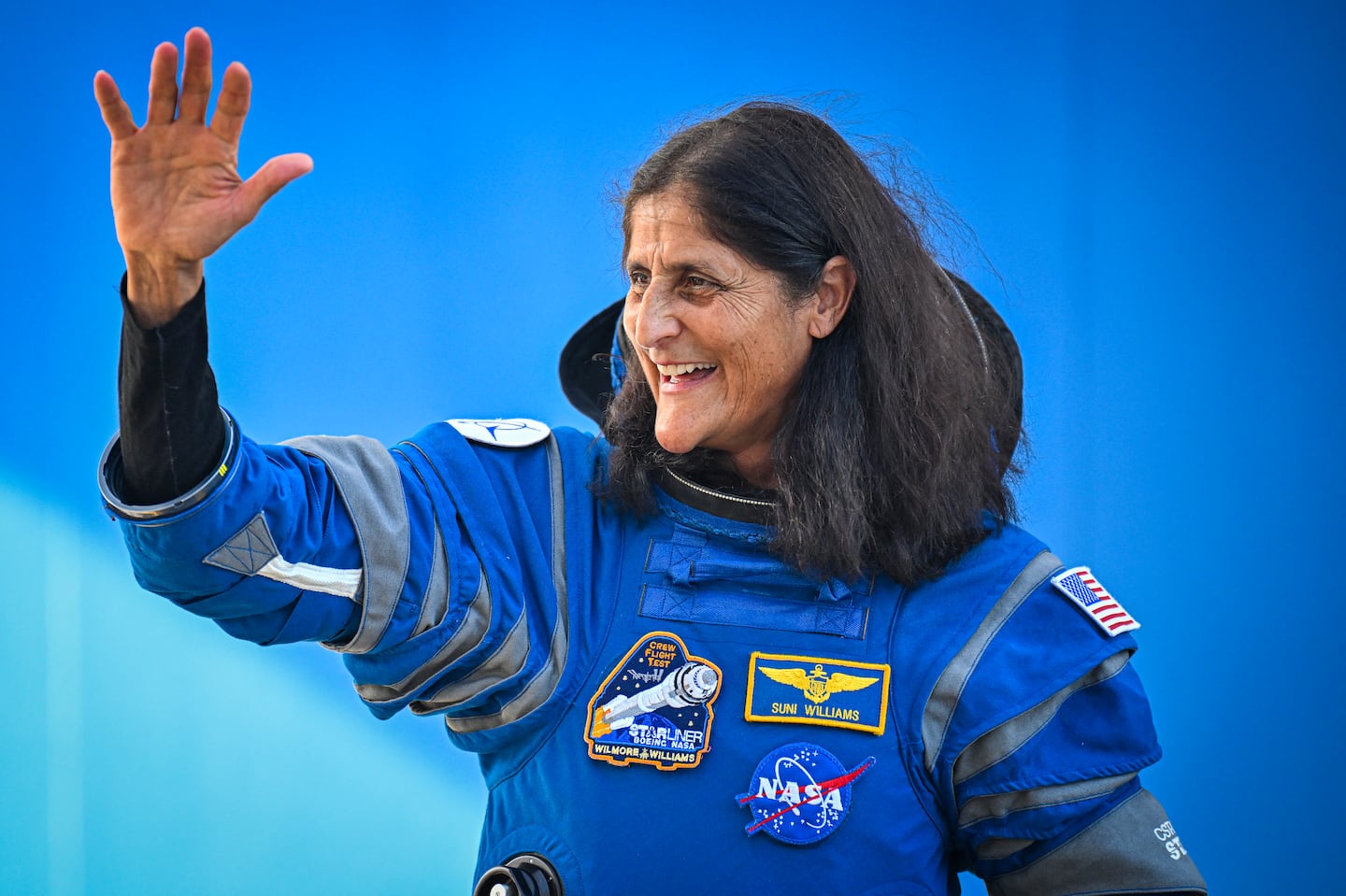 NASA astronauts Suni Williams waves as she prepares to depart the Neil A. Armstrong Operations and Checkout Building for Launch Complex 41 to board the Boeing CST-100 Starliner spacecraft in June.