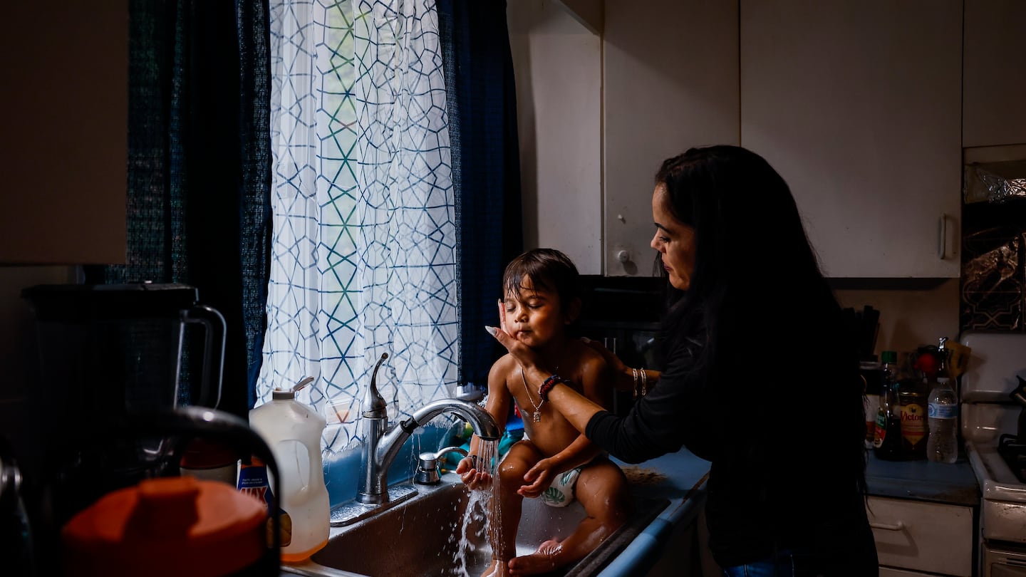 Gerrilee Thou rinses her 2-year-old son Ace at the kitchen sink in their Malden home. Thou, a mother of six, is struggling to make ends meet while her husband, Vibol, is detained by immigration authorities.