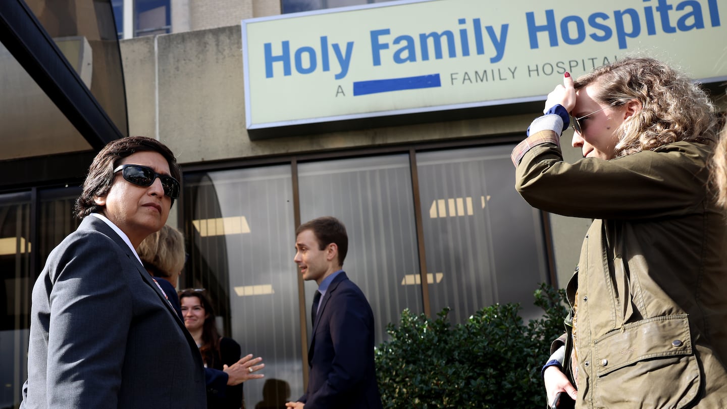 Dr. Abha Agrawal of Lawrence General Hospital, left paused underneath a sign for Holy Family Hospital that had been taped over to remove Steward’s name