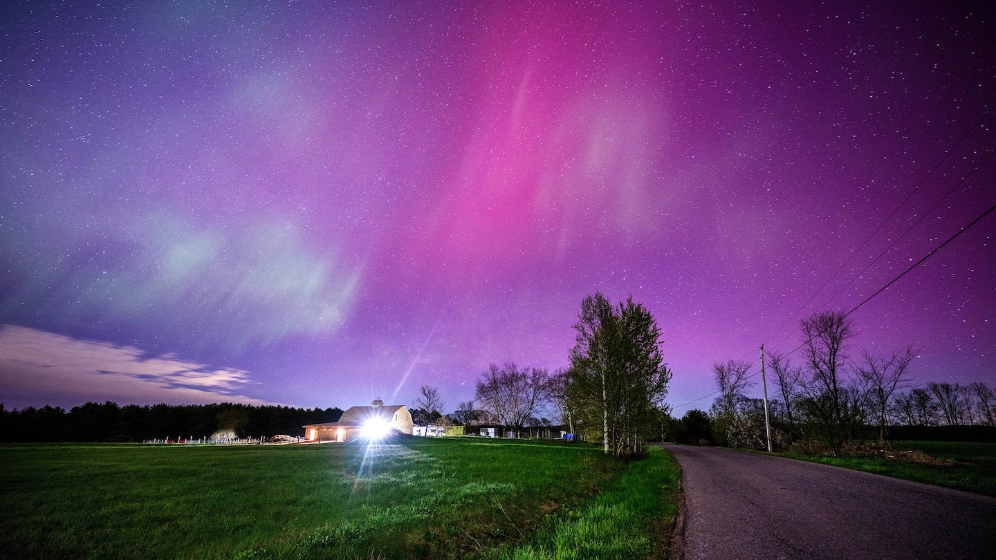 The aurora borealis fills the sky with pink and blue waves of color over a farmhouse in Mercer, Maine on May 11, 2024.