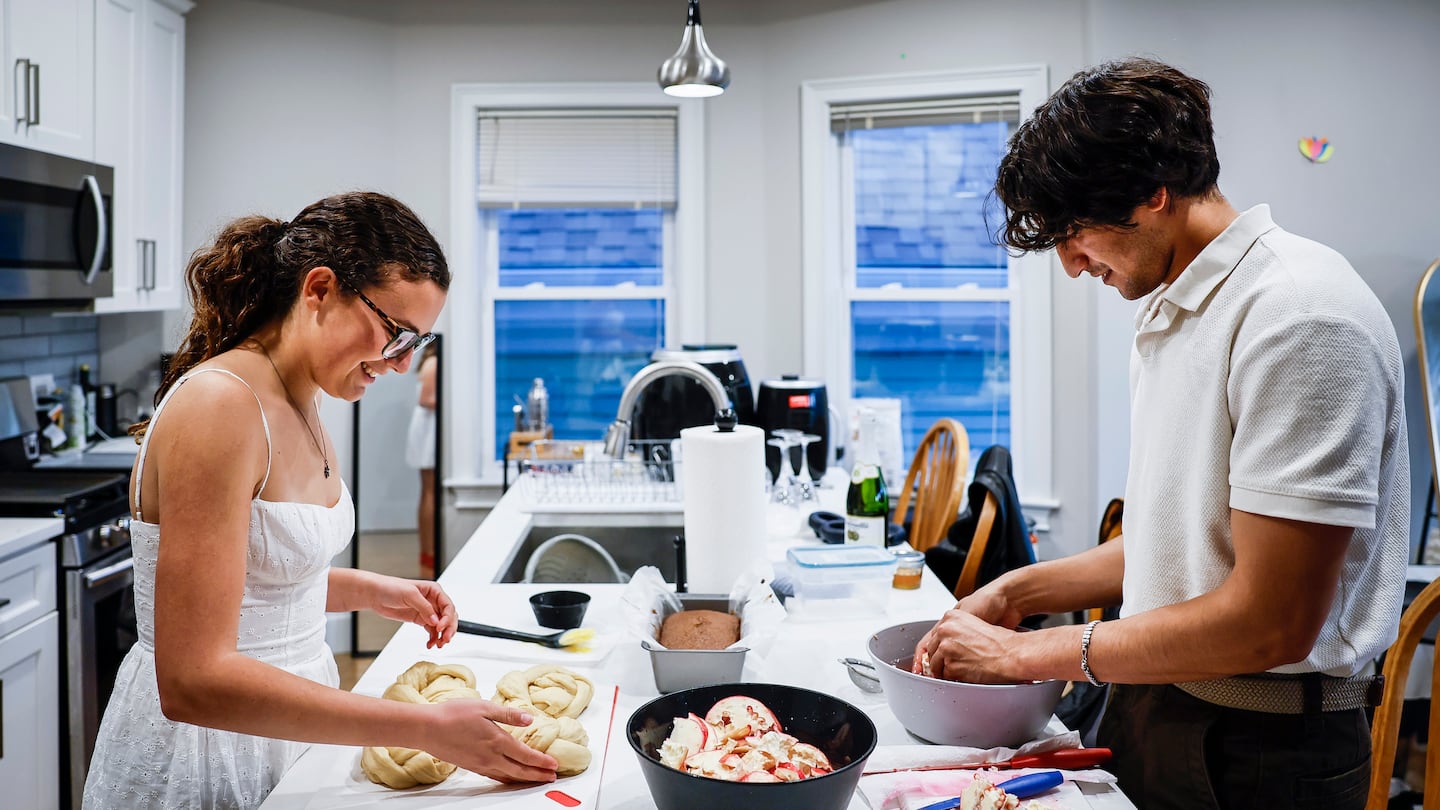 Devon White, left, prepared challah bread while Ethan Handel cleaned pomegranate seeds for a dinner in celebration of Rosh Hashana.