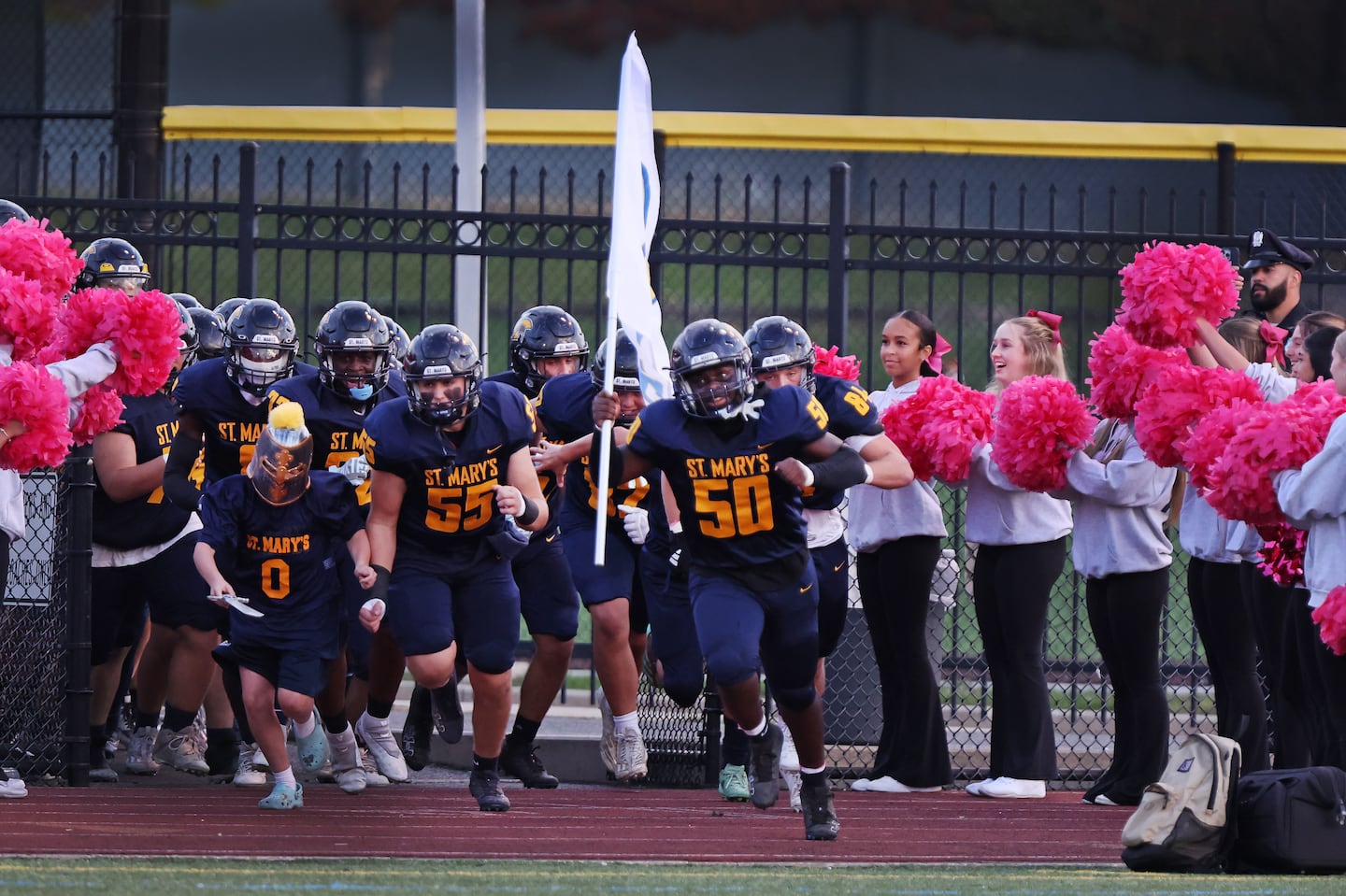 Adrian Lule (50) was the flag bearer as he leads the St. Mary's football team onto the field for Friday's Catholic Central matchup vs. Cathedral at the Manning Bowl. On the field, Lule registered a sack for a safety.