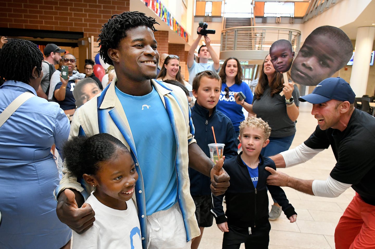 Olympic bronze medalist Frederick Thomas takes photos with children during a celebration of the gymnast at Stoughton High School on Sunday.