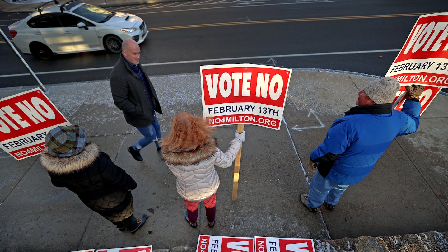 Organizers of the "no" campaign in Milton against new state-mandated zoning rules held signs outside of a polling location on the day of a townwide referendum in February.