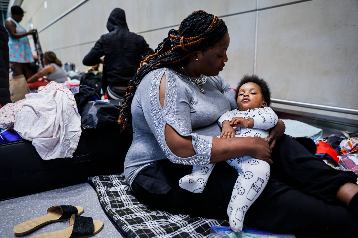 Sherlie Elisse held her baby, Elisonn Saint Juste, while resting on her blanket at Boston Logan Airport on July 2. They fled from Haiti when he was 1 month old, and the baby had to be hospitalized in Mexico.