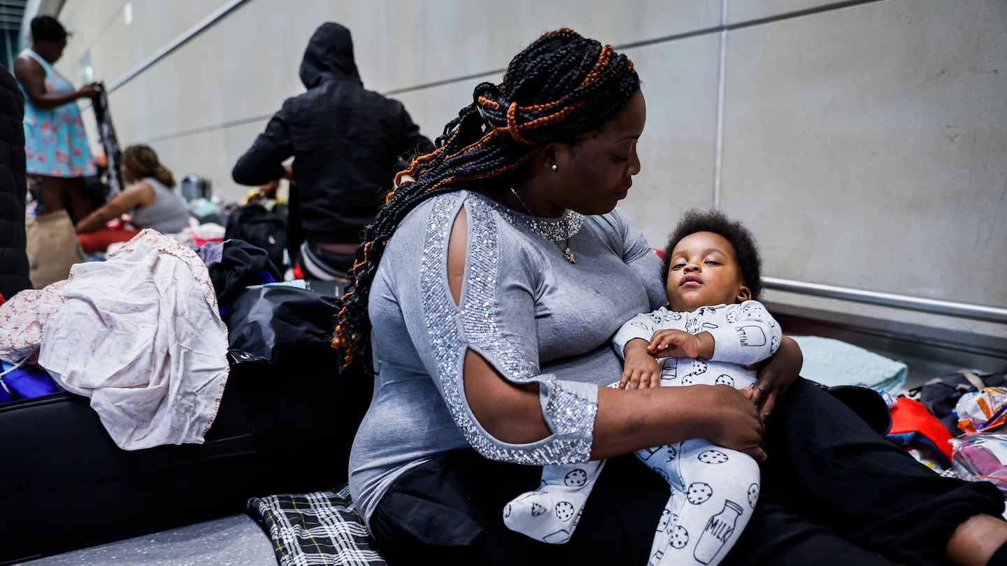 Sherlie Elisse held her baby, Elisonn Saint Juste, while resting on her blanket at Boston Logan Airport on July 2. They fled from Haiti when he was 1 month old, and the baby had to be hospitalized in Mexico.