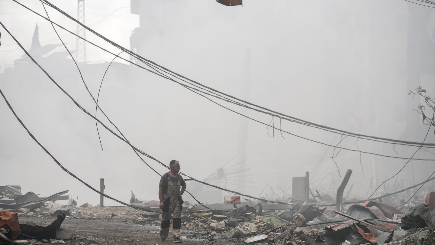 A man walks as smoke rises from destroyed buildings at the site of an Israeli airstrike in Choueifat, southeast of Beirut, Lebanon, on Oct. 7.