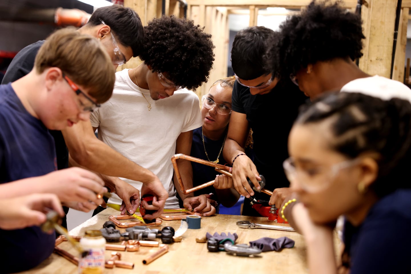 Kyra Matos (center), a junior at Greater Lawrence Tech, poked her head between her classmates in plumbing to get their opinion as the class worked to solder pipes.