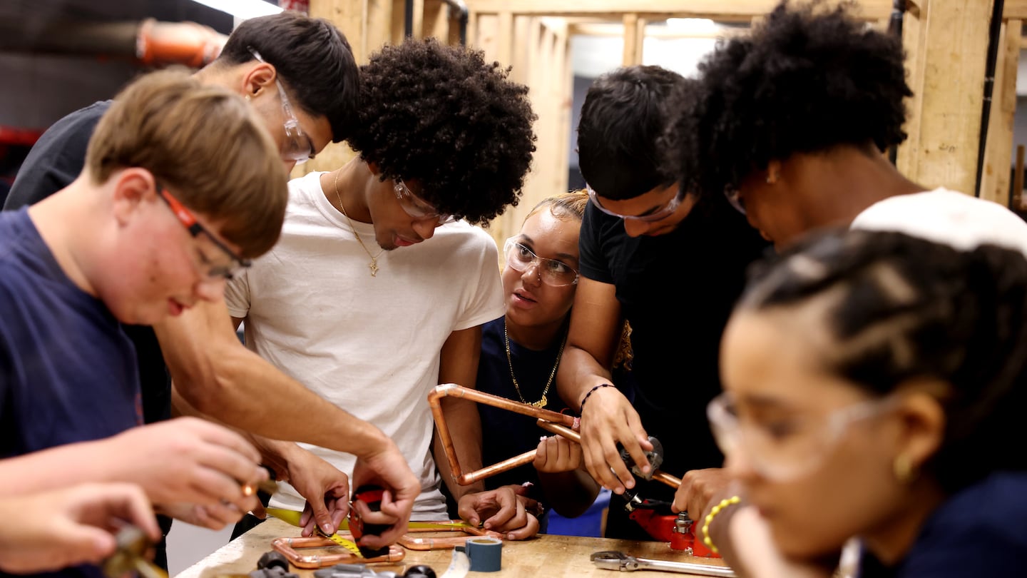 Kyra Matos (center), a junior at Greater Lawrence Tech, poked her head between her classmates in plumbing to get their opinion as the class worked to solder pipes.