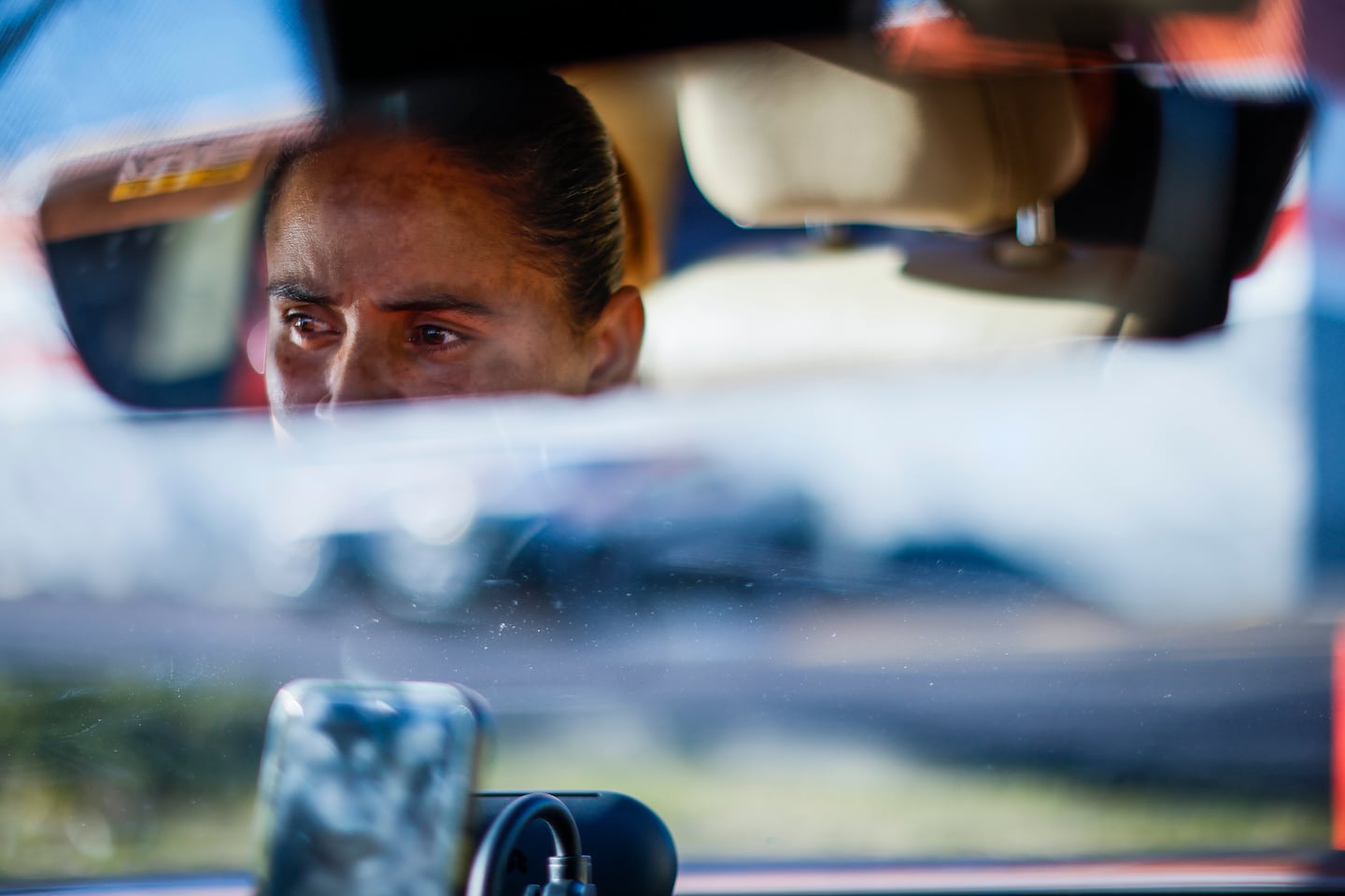 Victoria (last name withheld) posed for a portrait in her car, which she uses to drive for ride-hailing companies throughout the state.