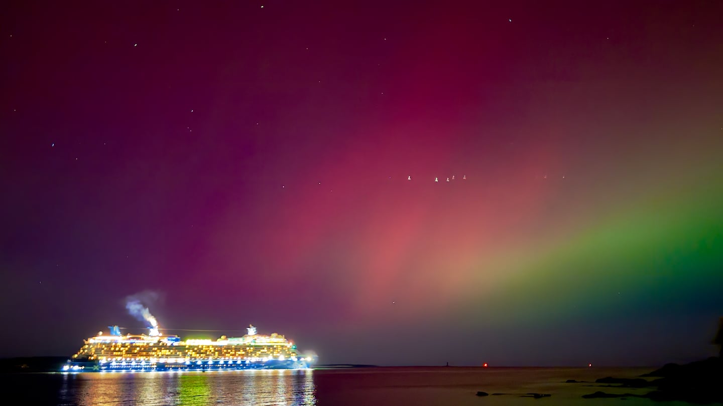 The aurora borealis shines over a cruise ship passing through Portland, Maine, Thursday night.