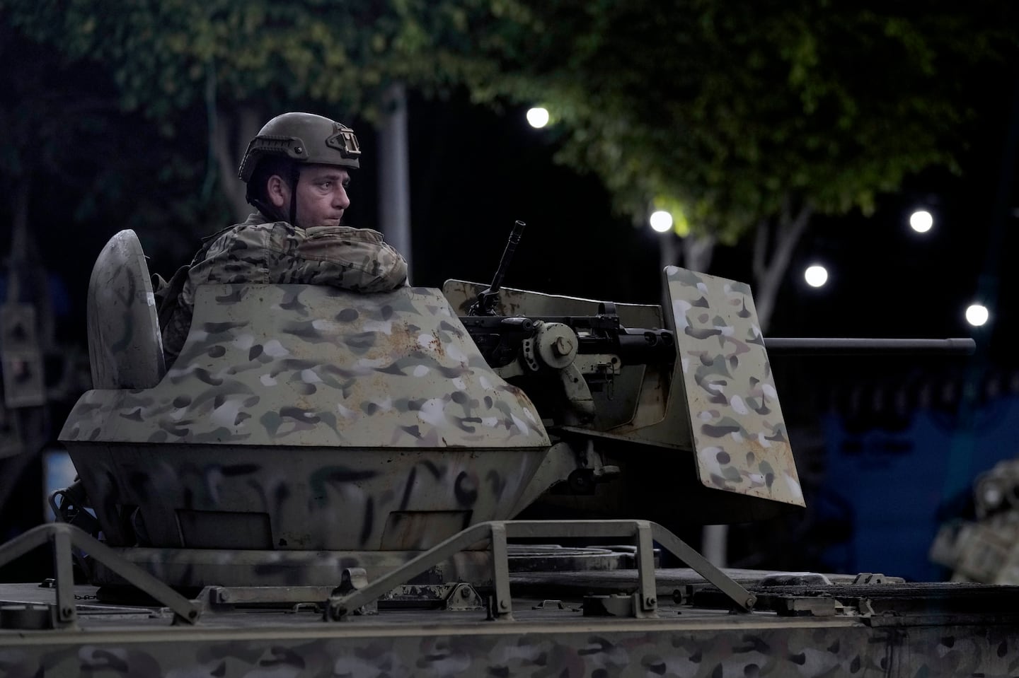 A Lebanese army soldier sits behind his weapon on the top of an armored personnel carrier at the site of an Israeli airstrike in Beirut's southern suburb, on Sept. 23.