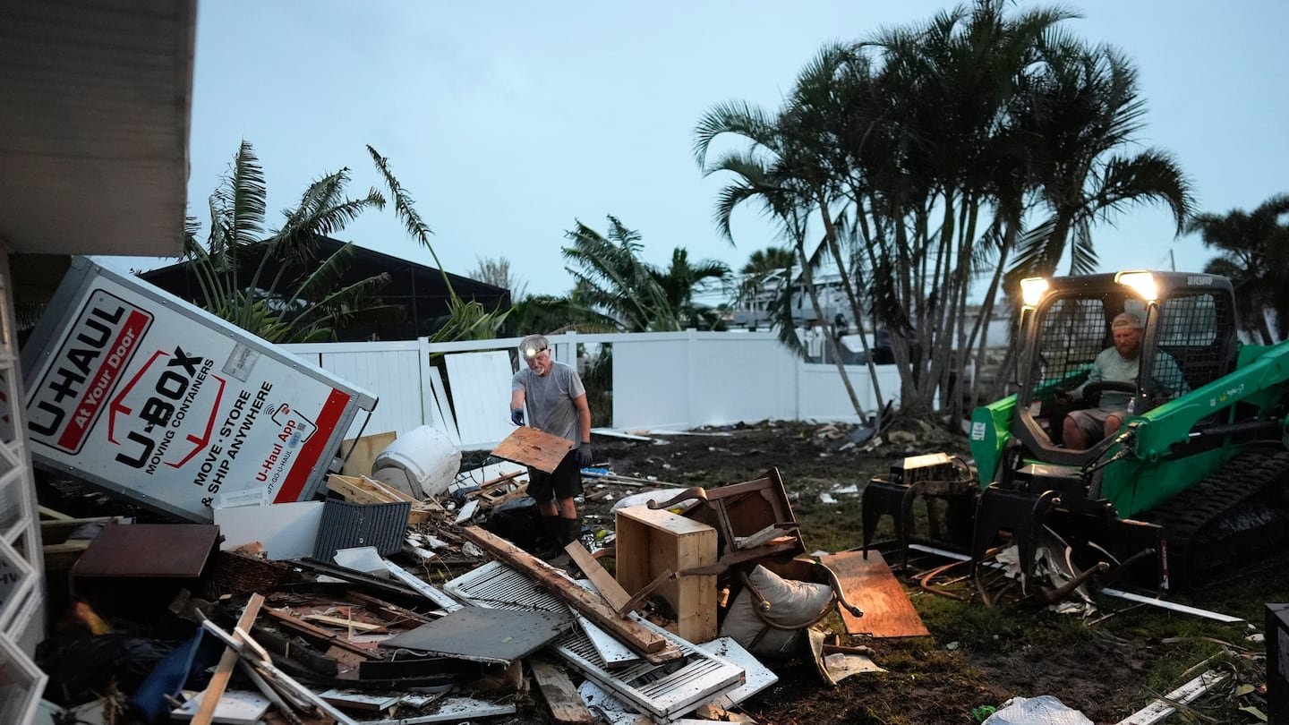 Homeowner Robert Turick, 68, left, and storm waste removal contractor Sven Barnes work to clear debris that Hurricane Milton storm surge swept from other properties into Turick's canal-facing back yard, in Englewood, Fla., on Oct. 11.