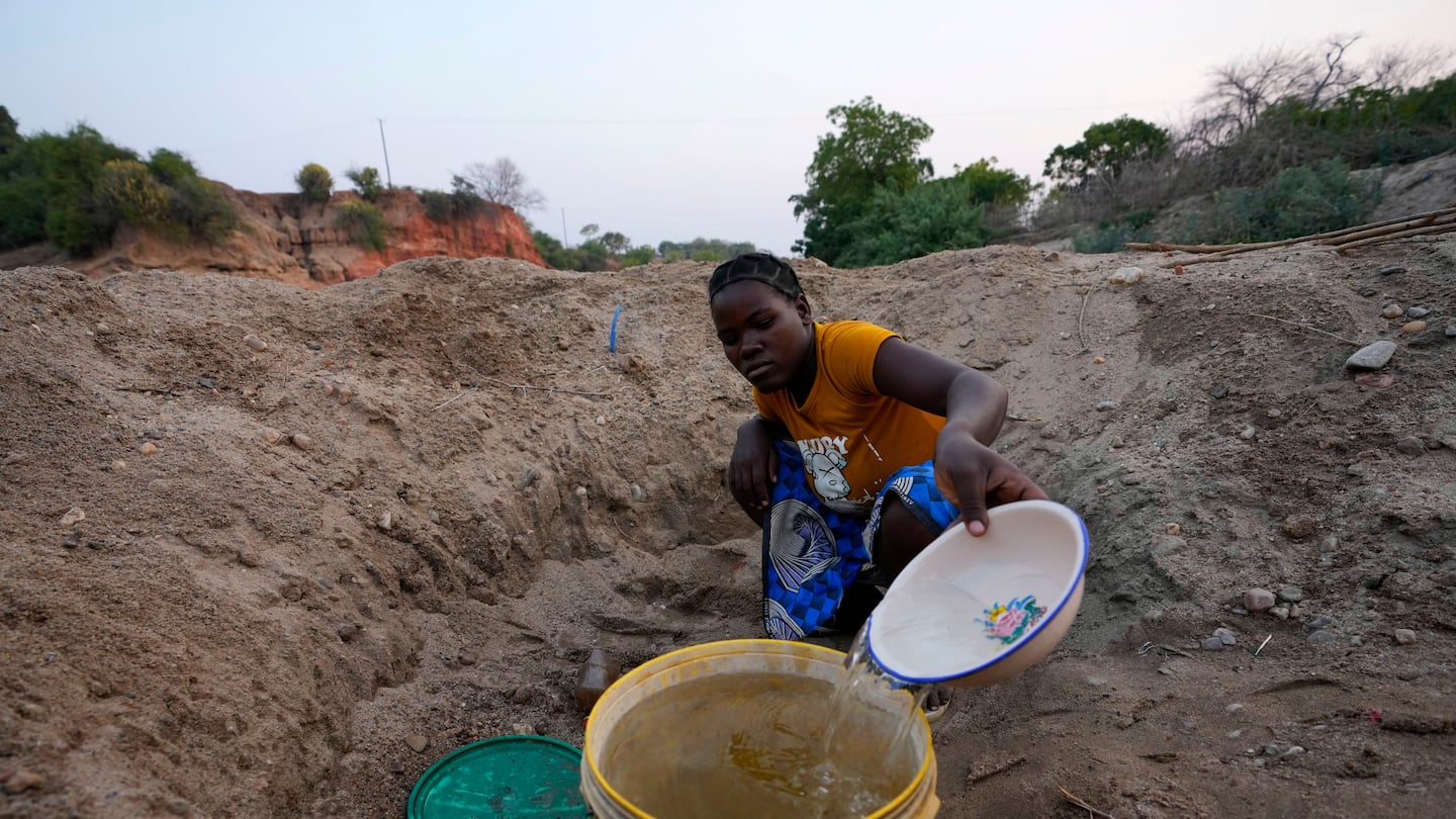 A woman scooped water from a hole she had dug in a dried up riverbed in Lusitu, Zambia last month.