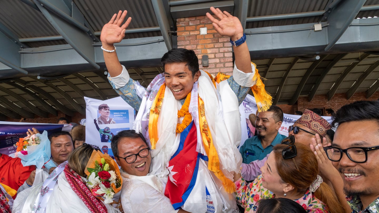 Minima Sherpa, father of 18-year-old Nima Rinji Sherpa, the youngest person to scale all the world’s 14 highest peaks, celebrates with his family upon his son's arrival at Tribhuvan International Airport in Kathmandu, Nepal, on Oct. 14.