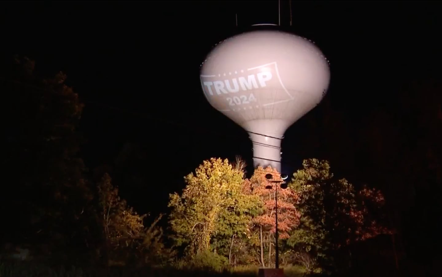 A Trump 2024 logo is projected onto a water tower in Hanson, MA.