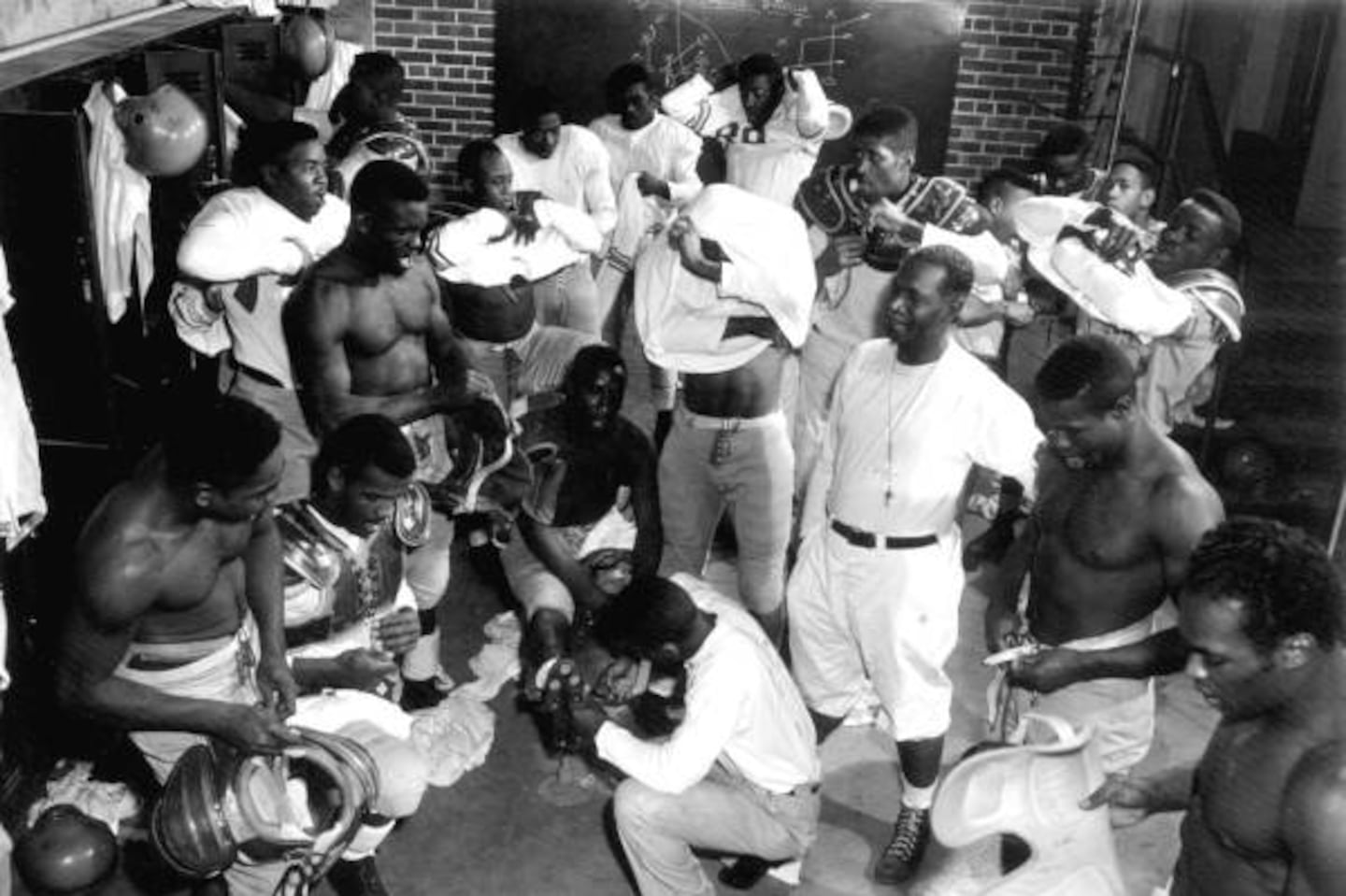 Florida Agricultural and Mechanical University coach Jake Gaither, wearing a white shirt and shorts, with his players in the locker room in 1953. Football, he once said, instilled “a belief in prayer, a faith in God."