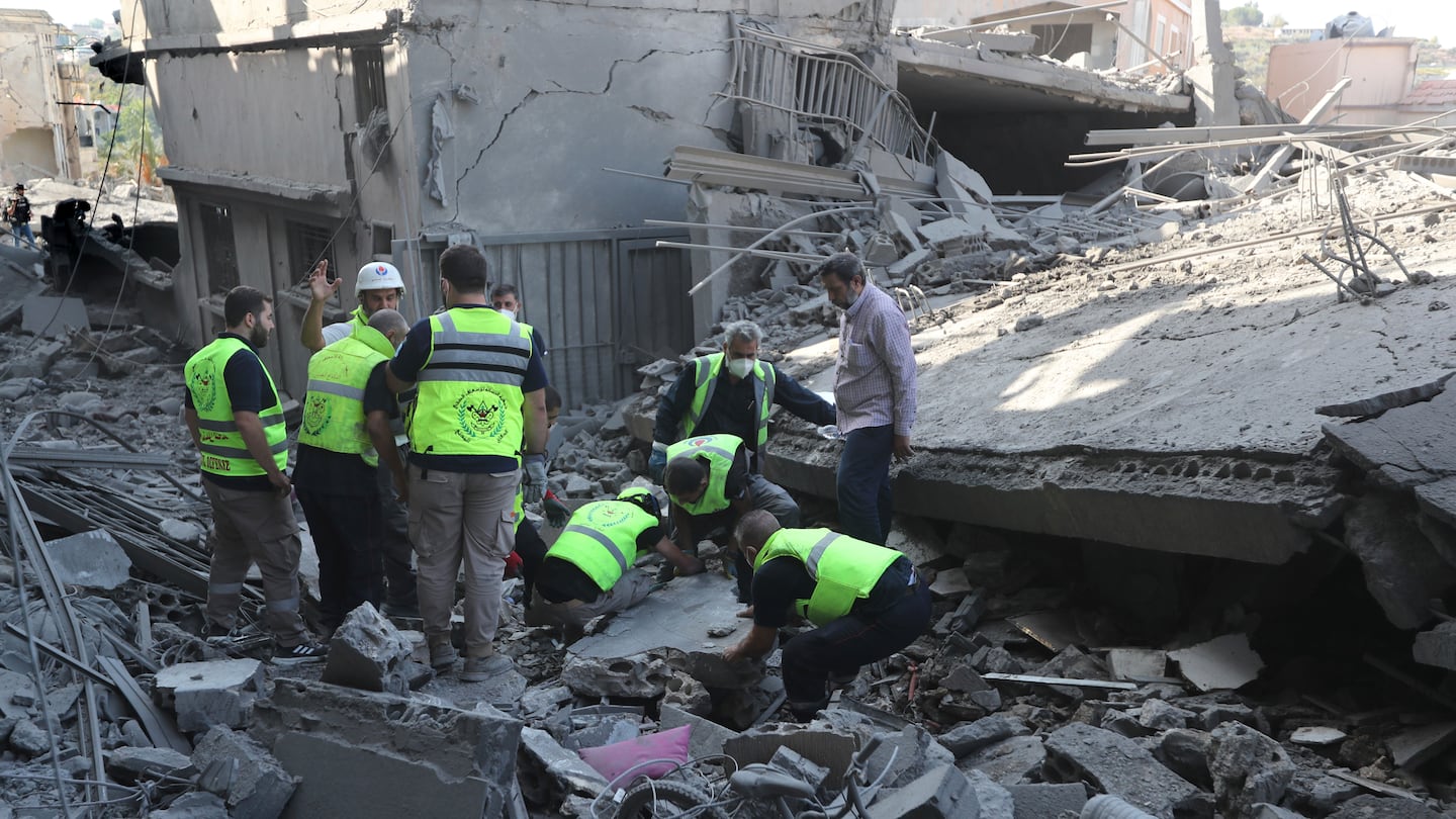 Rescue workers remove rubble, as they search for victims at the site that was hit by Israeli airstrikes in Qana village, south Lebanon, on Oct. 16.