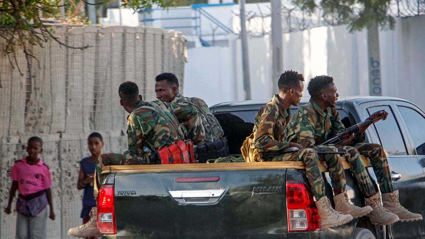 Children walk home, left, as Somalia police patrol near the scene of a suicide bomber attack at a café, in Mogadishu, Somalia, on Oct. 17.