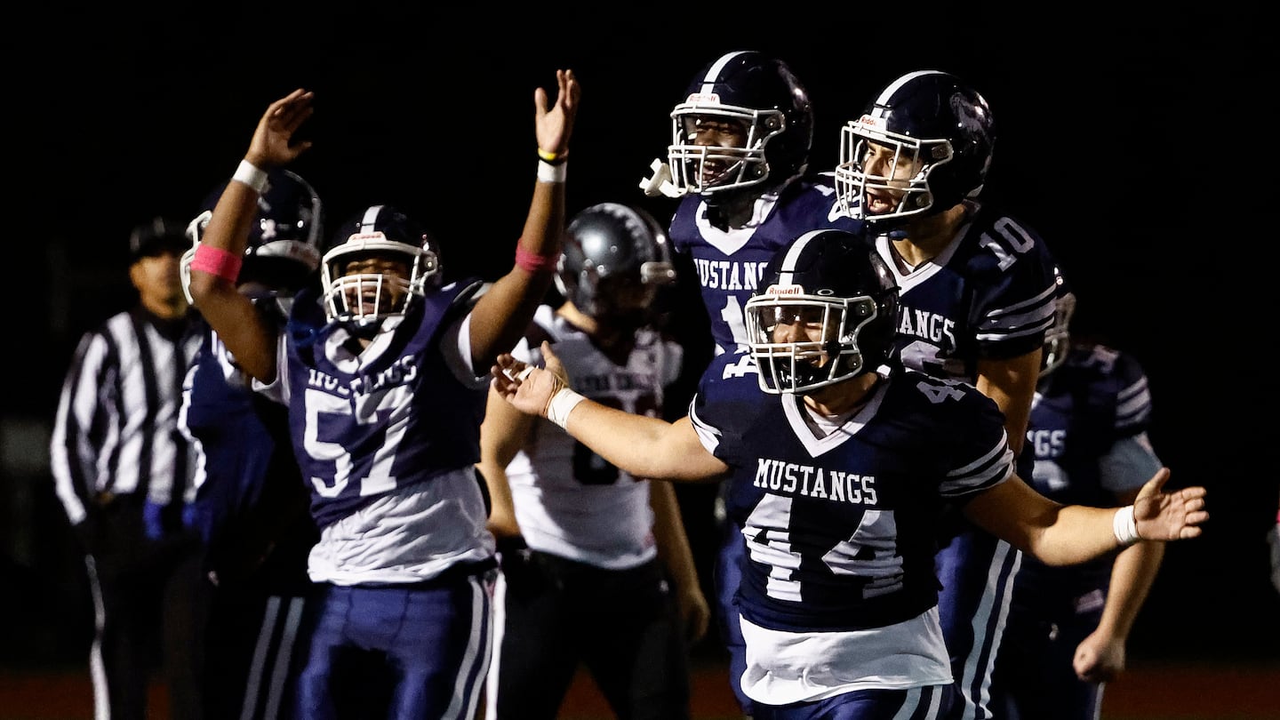 Medford players Ernesto Orphe (No. 57), Prince Exavier, Justin Marino (10) and Joshua Santos (44) celebrate after the final whistle of their 20-18 Greater Boston League home win over Lynn English Thursday night