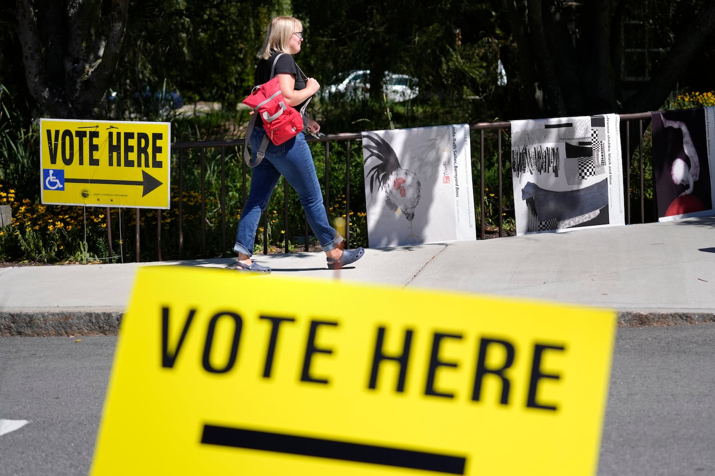 A person walks past polling station signs outside the Newton Free Library during Massachusetts state primary voting in September, in Newton, Mass.