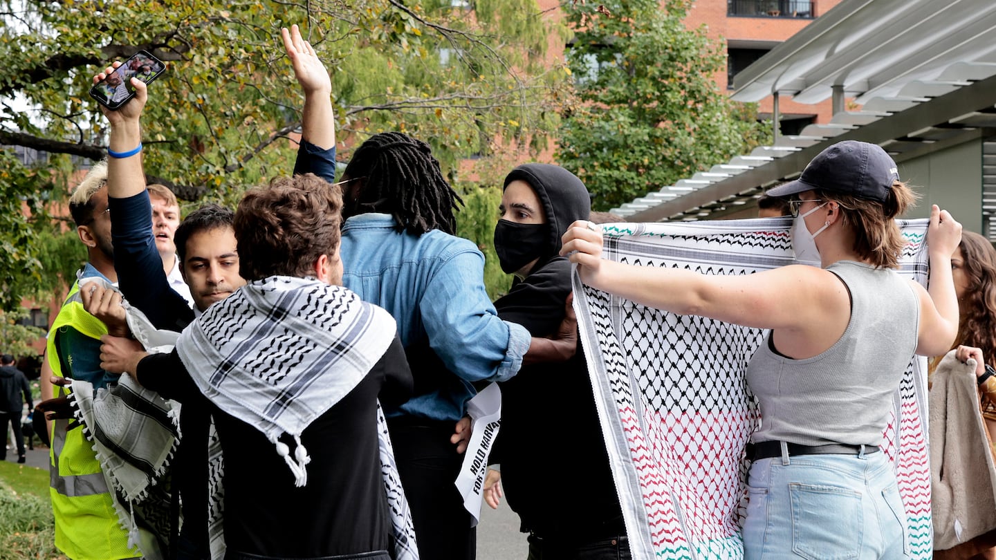 A group of demonstrators, including Harvard students Ibrahim Bharmal (left with vest) and Elom Tettey-Tamaklo (blue shirt), surrounded Israeli student Yoav Segev (hands up) at a pro-Palestinian protest on Oct. 18, 2023, at Harvard Business School.