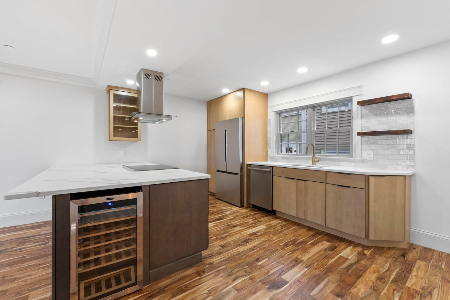 The kitchen offers maple cabinets topped with quartz and a backsplash of porcelain that glistens in the sun from the windows above the sink.