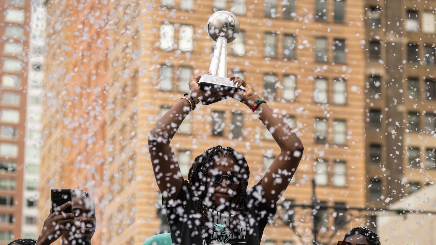 As the ticker tape comes down, the Liberty's Jonquel Jones holds up her Finals MVP Trophy as she and her New York teammates make their way through the Canyon of Heroes in Manhattan Thursday to celebrate their WNBA Championship. 