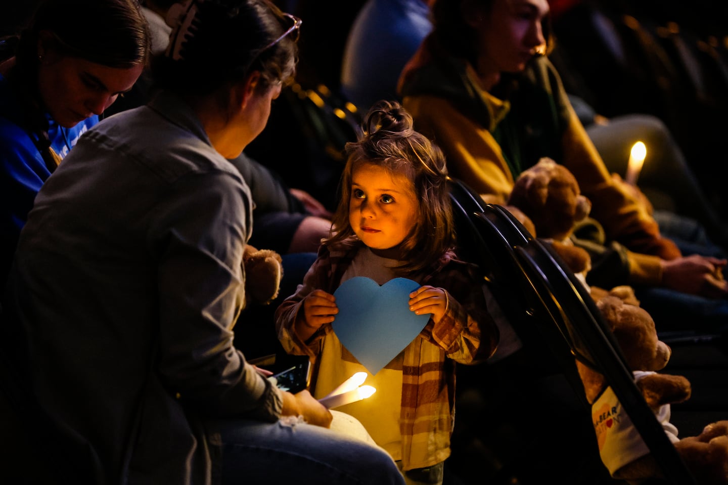 A young girl with a blue heart, symbolizing Lewiston's strength, during Friday's memorial service at The Colisée marking one year since the mass shooting that killed 18 people.