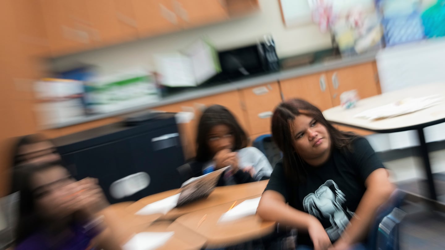 Alisson Ramírez, right, listens to her social studies teacher during class, on Aug. 28, in Aurora, Colo.