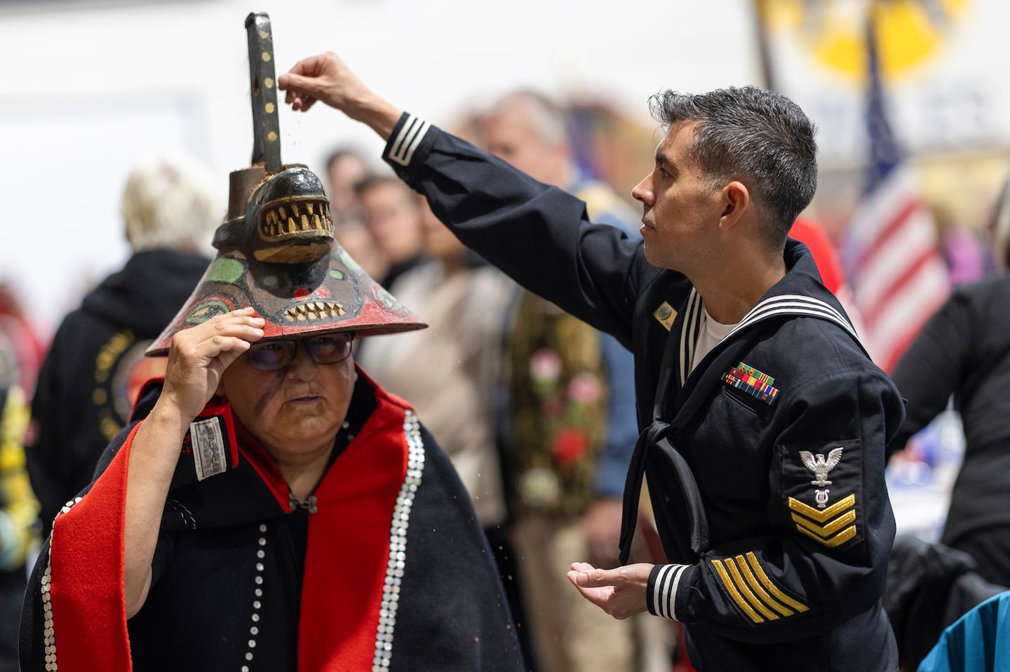 A member of the US Navy sprinkles tobacco on top of a killer whale clan hat, which is considered to bring good fortune, during a Navy ceremony, on Oct. 26, in Angoon, Alaska, to apologize for the 1882 military bombing of the Tlingit village.