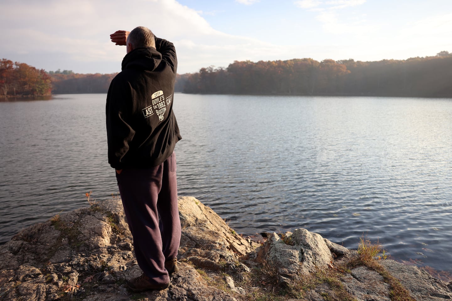 A man shielded his eyes as he looked out over Wright’s Pond in Medford where smoke from a brush fire in Salem could be seen and the smell was heavy in the air.