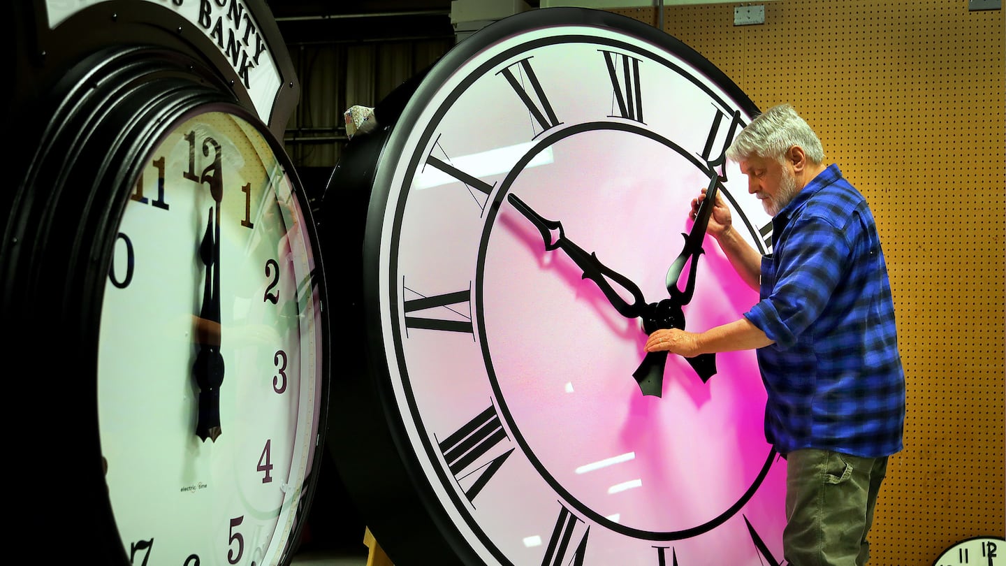 Scott Gow adjusted the hands on a six foot canister clock at the Electric Time Company in Medfield. They have  built and repaired tower, post and building clocks for nearly 100 years. This year, the clocks go back one hour on November 3rd.