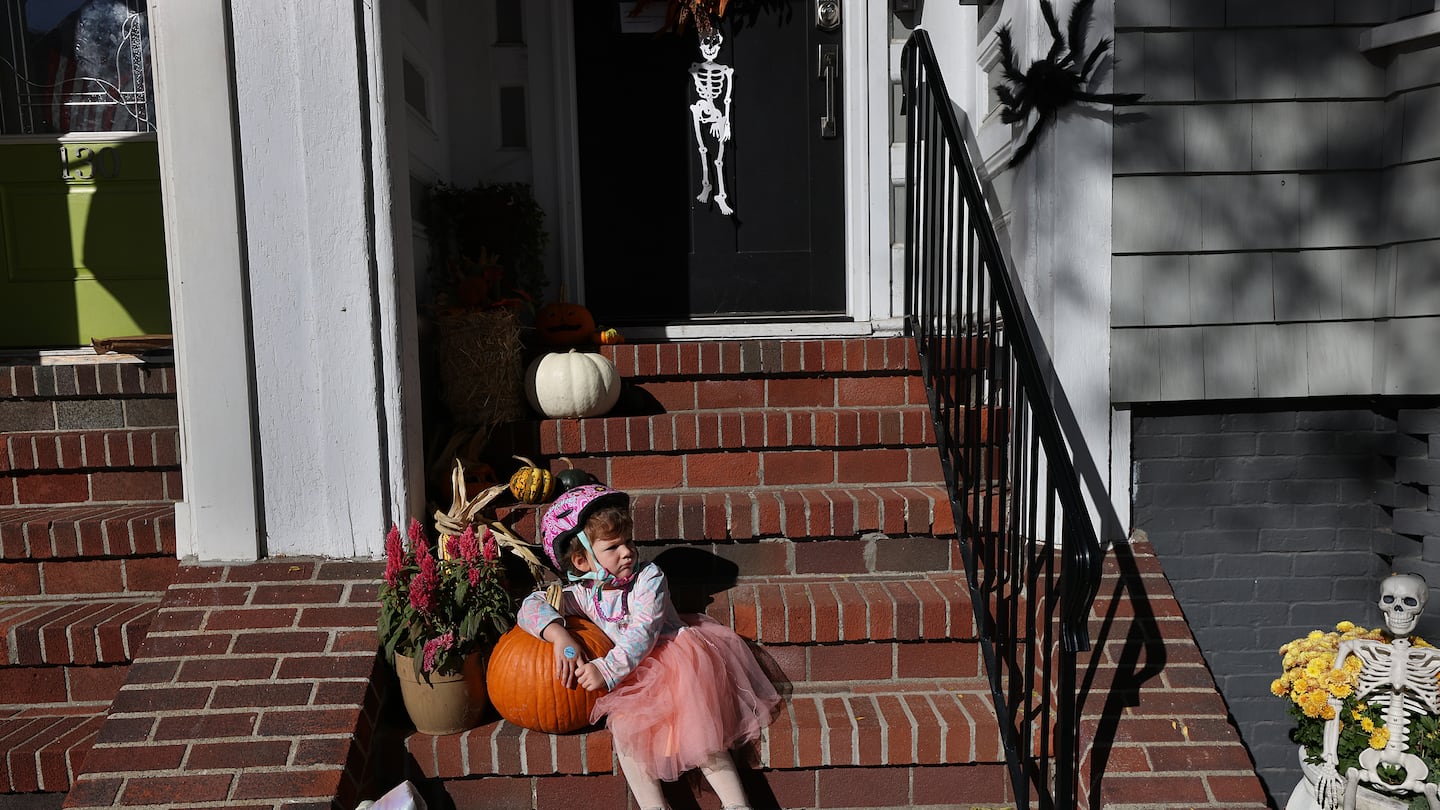 Three-year-old Dorothy Davis rests on her front steps in South Boston with her pumpkins and Halloween decorations.