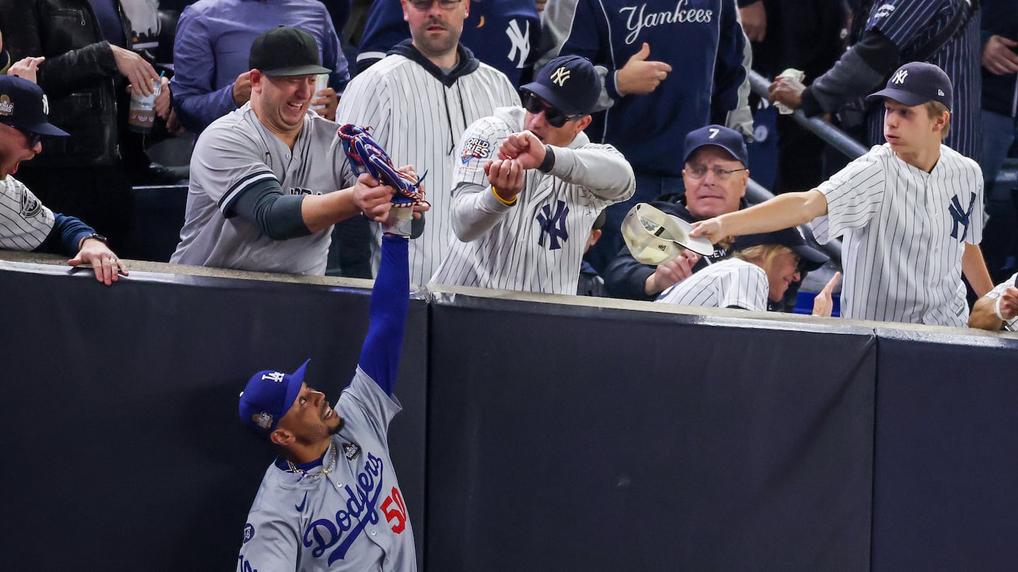 Fans interfere with Dodgers right fielder Mookie Betts as he attempts to catch a fly ball in foul territory in the first inning of Tuesday night's Game 4 of the World Series at Yankee Stadium. 