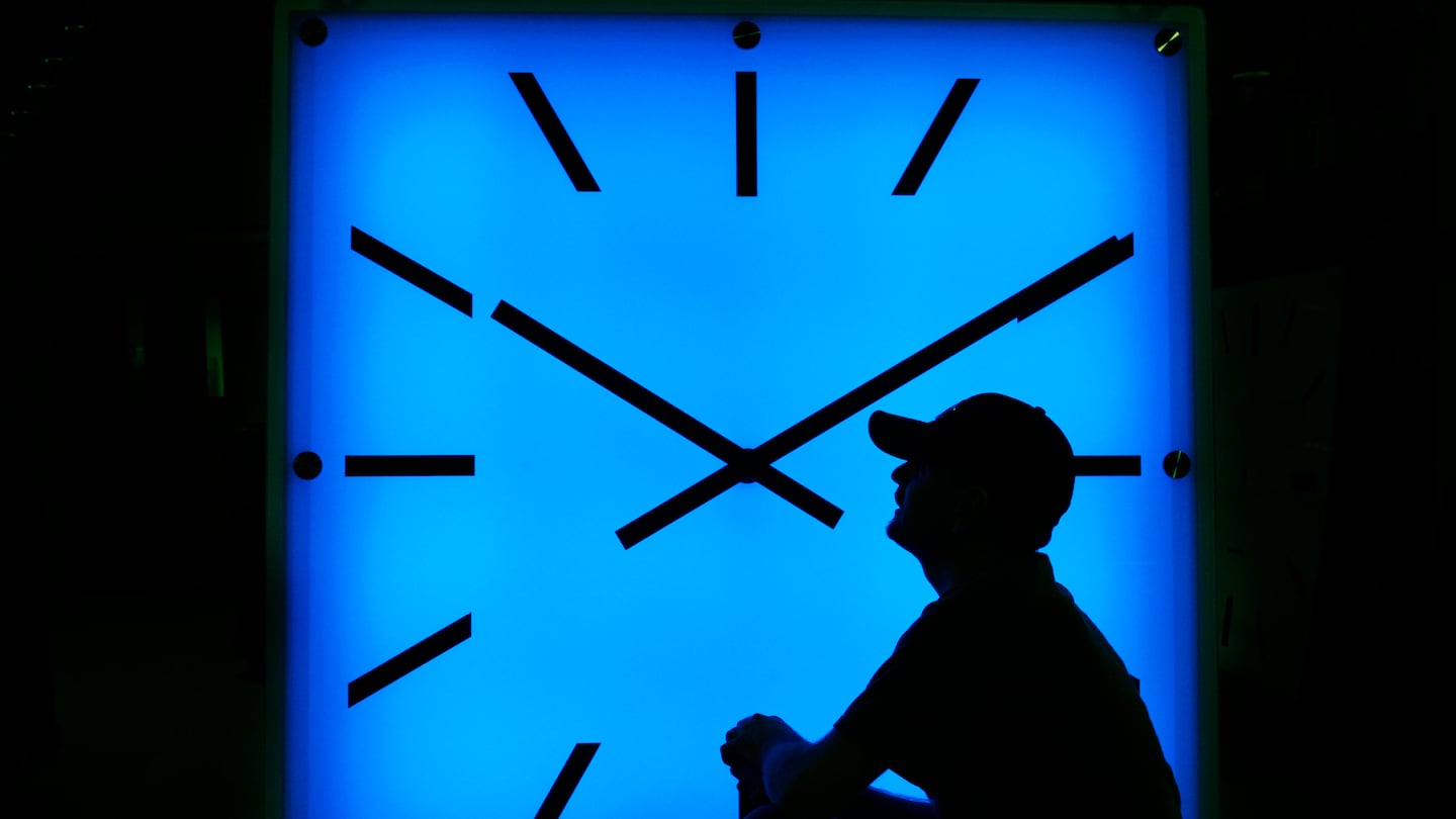 An Electric Time Company employee adjusts the color on a clock.