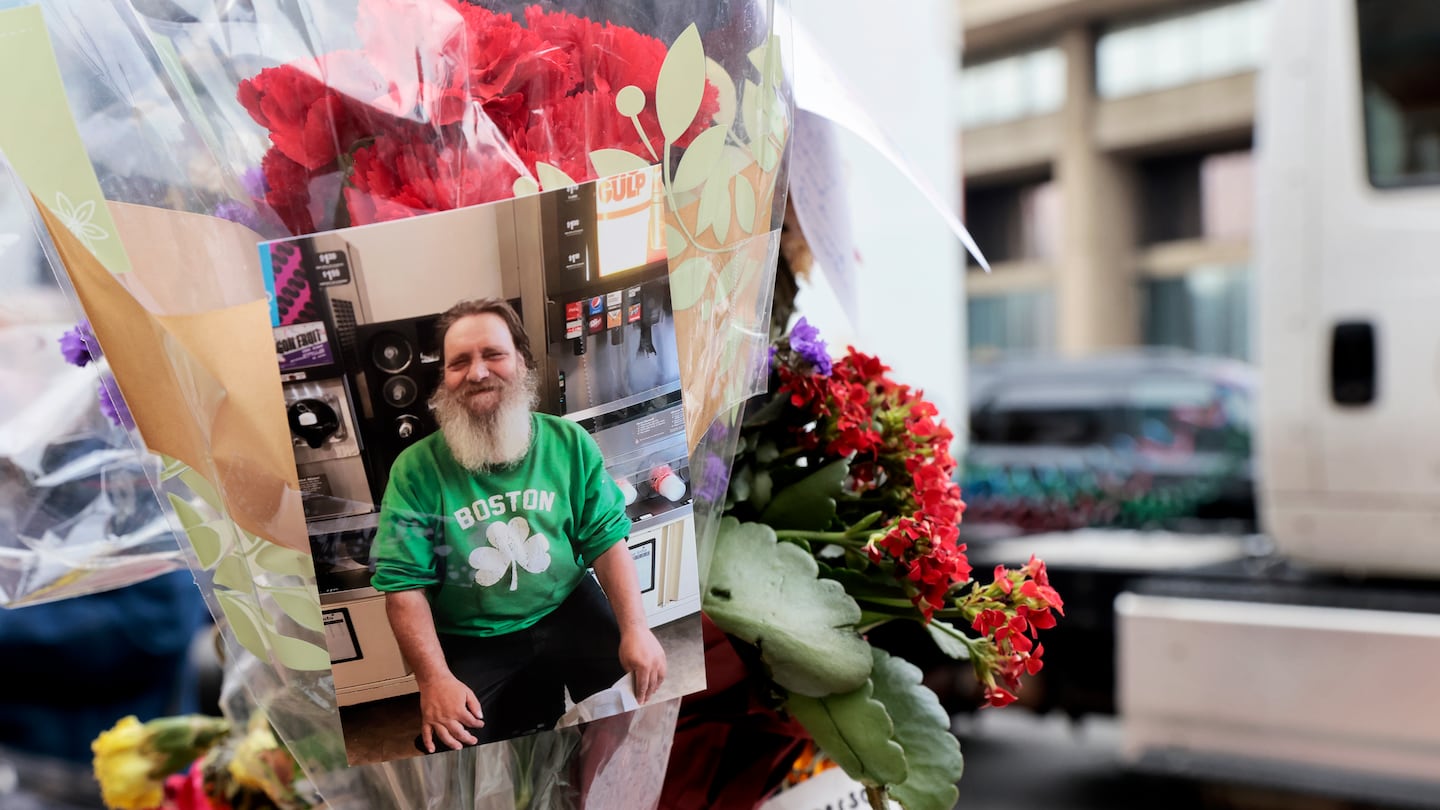 Flowers, cards, and photos were added to a memorial post during a remembrance for Glenn Durkee.