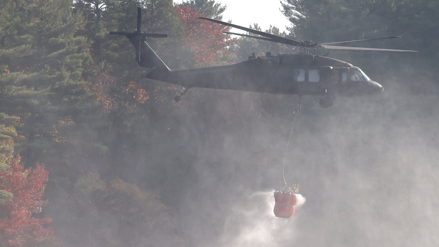 The Massachusetts Army National Guard drops water on a wildfire surrounding Middleton Pond on Tuesday.