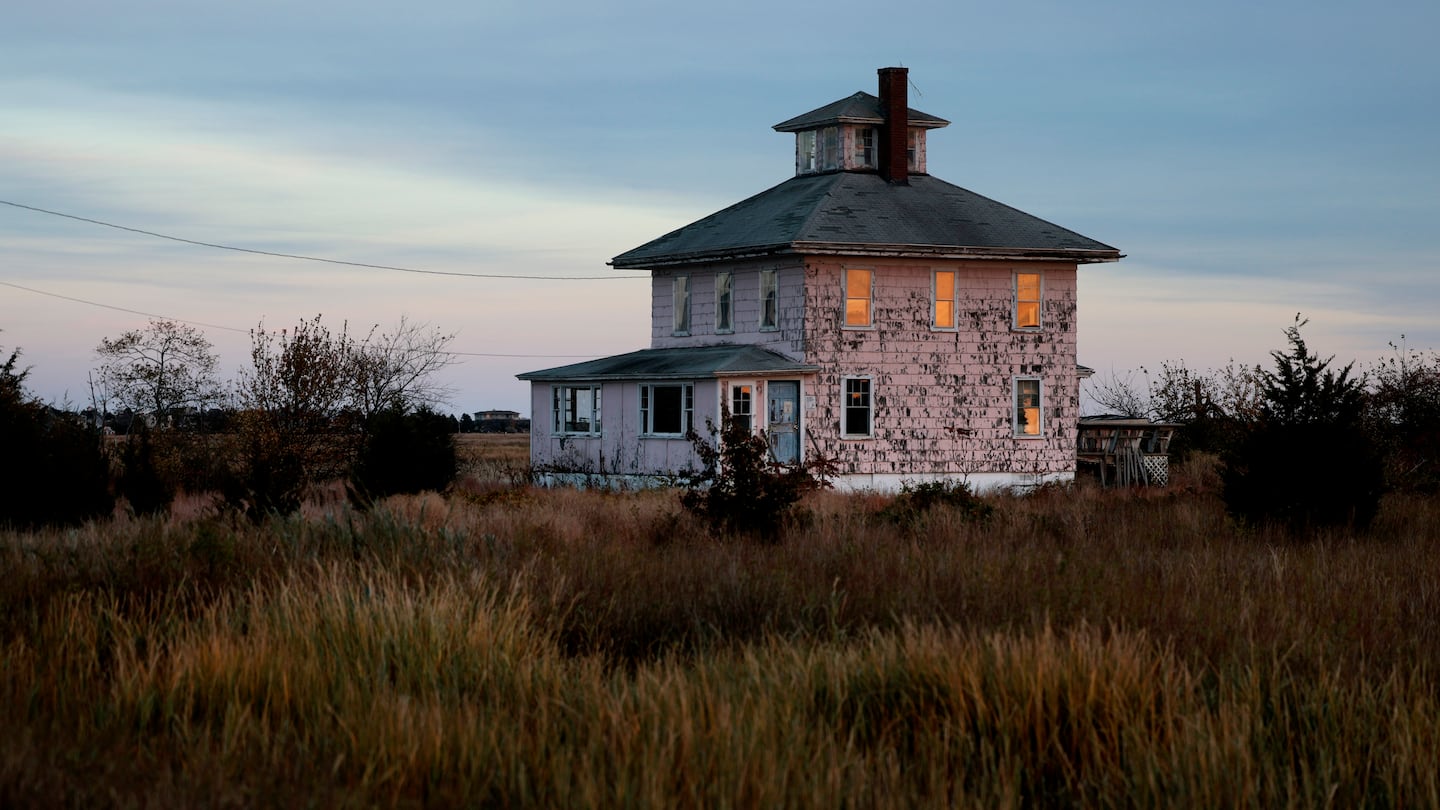 The setting sun is reflected in the windows of the iconic Pink House on the causeway to Plum Island. The building is owned by US Fish and Wildlife, and they've announced they are tearing it down.